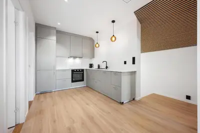 a kitchen with white cabinets and a wooden floor at Newly renovated apartment in the heart of Bergen city center in Bergen