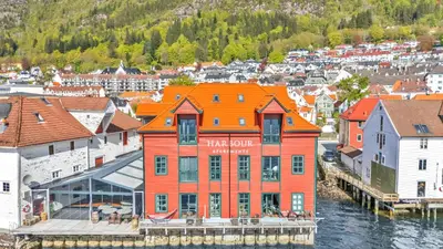 an orange building on the water in a city at Heimby - Seaside View Luxury - Free Parking in Bergen