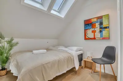 a white bedroom with a bed and a chair at Heimby - Seaside Luxury - Free Parking in Bergen