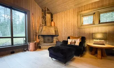 a living room with a fireplace and a chair and a table at Mountain Escape Near Gulsrud With Historical Charm in Eggedal