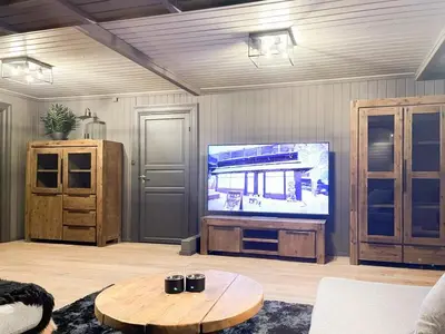 a living room with a flat screen tv and a table at Mountain Escape Near Gulsrud With Historical Charm in Eggedal