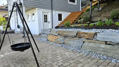 a black pot on a tripod next to a stone wall at Morgensolen in Bergen