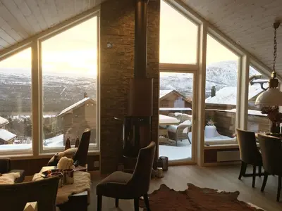 a living room with a view of a mountain through windows at Ski-in ski-out high standard cabin, 3 bedroom in Oppdal