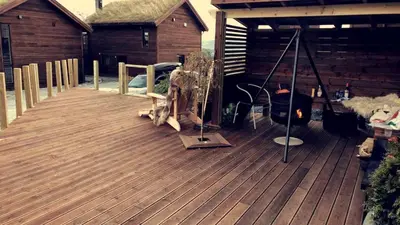 a wooden deck with a fireplace and a house at Ski-in ski-out high standard cabin, 3 bedroom in Oppdal