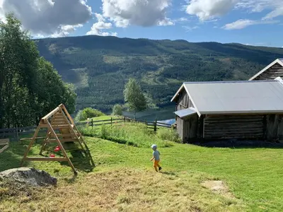 a young child standing in the grass in front of a barn at Architect designed sleeping box in barn in Nos