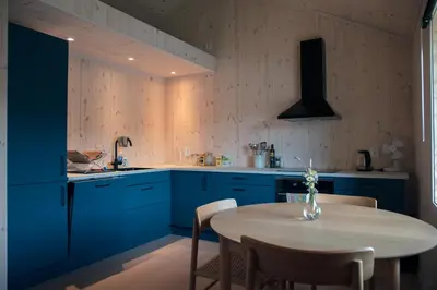 a kitchen with blue cabinets and a table with chairs at Architect designed sleeping box in barn in Nos