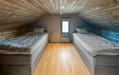 two beds in a room with a wooden floor at Amazing Home In Løten in Løten