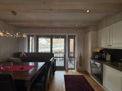 a kitchen and living room with a table and a kitchen and a dining room at Ski-in ski-out at Kikut, Geilo, apartment with sauna in Geilo