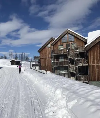 a person on skis in the snow next to a building at Ski-in ski-out at Kikut, Geilo, apartment with sauna in Geilo