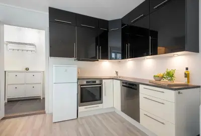 a kitchen with white appliances and black cabinets at Apartment in the Heart of Ålesund in Ålesund