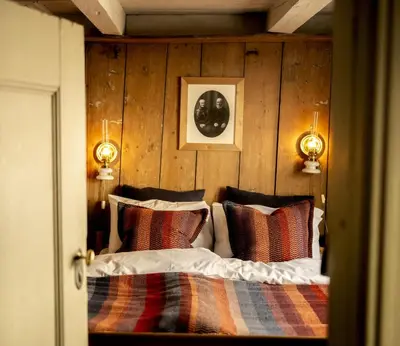 a bedroom with a bed with a wooden wall at Per Amundsagården in Røros