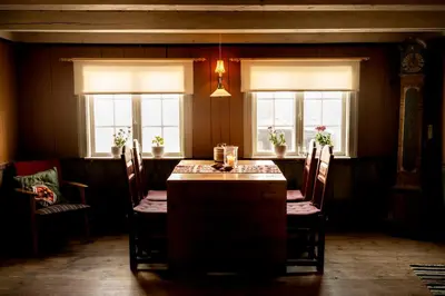 a dining room with a table and chairs and windows at Per Amundsagården in Røros
