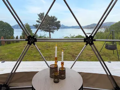 two candles sitting on a table in front of a window at Idyllisk overnatting i dome ved sandstrand in Langenes