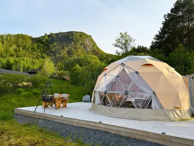 a tent sitting on a wooden deck with a table at Idyllisk overnatting i dome ved sandstrand in Langenes