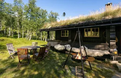 a log cabin with a table and chairs and a fire at Mountain Cabin With Cross-Country Trails In Rauland in Rauland