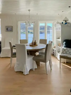 a white dining room with a table and chairs at Coastal Cabin With Panoramic Views In Høvikstranda
