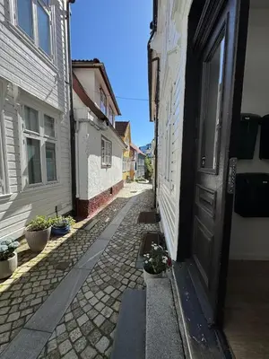 an alley with an open door in a building at Bo i Bergens eldste smau på Nøstet - sentralt og rolig in Bergen
