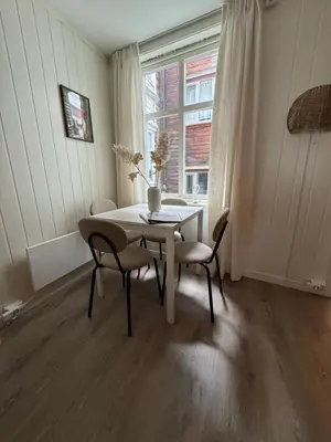 a dining room with a table and chairs and a window at Bo i Bergens eldste smau på Nøstet - sentralt og rolig in Bergen