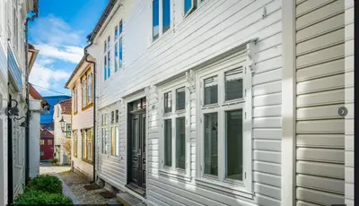 a row of white buildings on a street at Bo i Bergens eldste smau på Nøstet - sentralt og rolig in Bergen