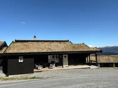 a black house with a grass roof with two chairs at Modern apartment in Voss in Vossevangen