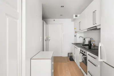 a white kitchen with white cabinets and a wooden floor at Bergen Beds Apartment I Right Behind Bryggen! in Bergen