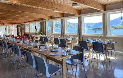 a row of tables and chairs in a room with windows at Knausen in Ørsta