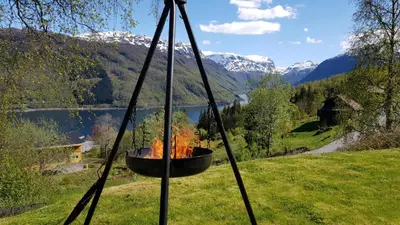 a fire pit with a view of a lake and mountains at Leilighet i Røldal in Håra