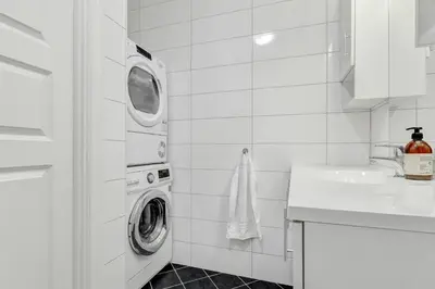 a white bathroom with a washing machine and a sink at Central Charm in Bergen