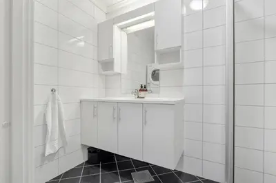 a white bathroom with a sink and a mirror at Central Charm in Bergen