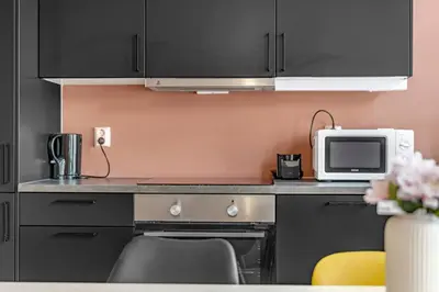 a kitchen with black cabinets and a microwave at Bryggen Gateway Homes in Bergen