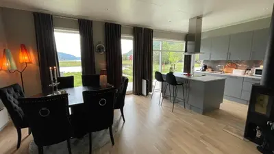 a kitchen and dining room with a table and chairs at Strandhus i idylliske omgivelser in Batnfjordsøra