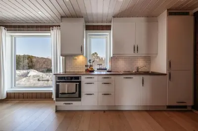 a kitchen with white cabinets and a large window at Beautiful City Cottage at Geilotunet in Hol