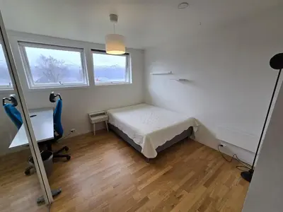 a bedroom with a bed and a desk and two windows at 6 Bedroom House in Ålesund