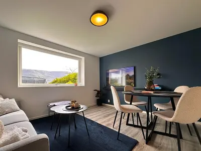 a living room with a table and chairs and a window at Cozy basement apartment in Ålesund