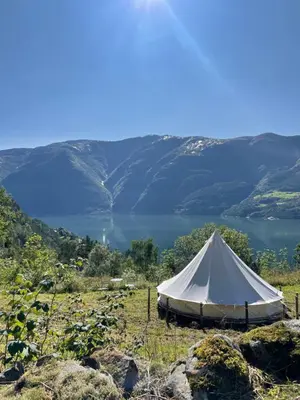 a white tent in a field with a lake at Glamping Kalhagen in Vangsbygd