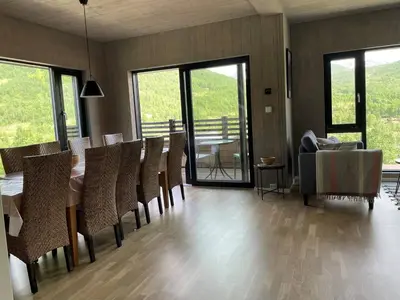 a dining room with a table and chairs and glass doors at Helgatunlia - Leilighet 1 in Vossevangen