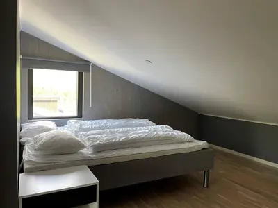 a bed with white sheets and a window in a room at Helgatunlia - Leilighet 1 in Vossevangen