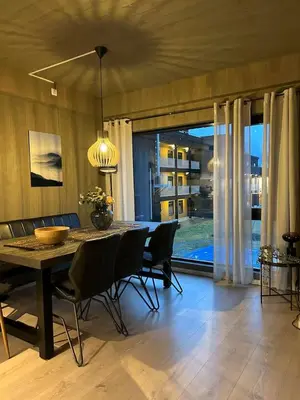 a dining room with a table and chairs and a large window at Helgatunlia - Leilighet 2 in Vossevangen