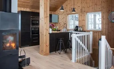 a kitchen with a fireplace in a wooden house at Modern Mountain Cabin With Views At Filefjell in Tyinkrysset