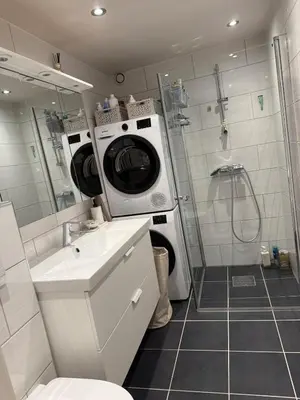 a bathroom with a washing machine and a sink at Sentral leilighet i Åsane in Sørebø