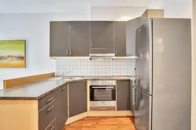 a kitchen with a stainless steel refrigerator and cabinets at Heimby - Roomy Studio w Free parking and SeaView in Bergen