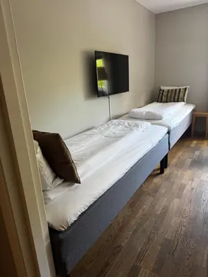 two beds in a room with a tv on the wall at Dølaheimen in Lillehammer