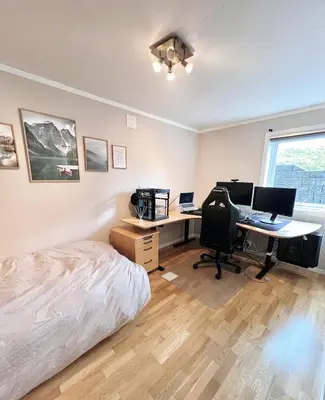 a bedroom with a bed and a desk with two computers at 2BR, 2 parking spots, EV-charger and home office in Trondheim