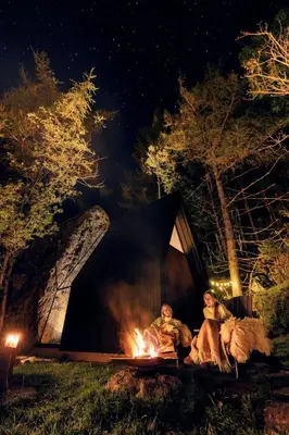 two people sitting around a fire in a tent at Spectacular Fjord getaway - The Forge in Leirgulen