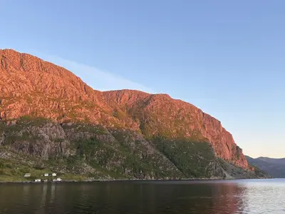 a mountain on the shore of a body of water at Spectacular Fjord getaway - The Forge in Leirgulen