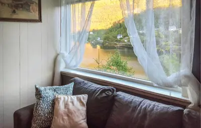 a couch sitting in front of a large window at Awesome Home In Sævareid With Lake View in Sævareid