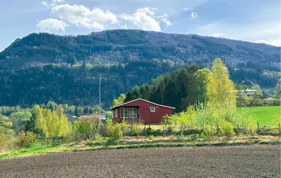 a red house in a field with a mountain at 1 Bedroom Awesome Home In Vik I Sogn in Vikøyri