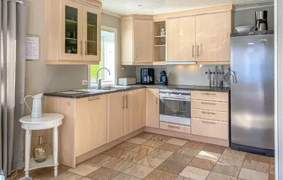 a kitchen with wooden cabinets and a stainless steel refrigerator at 3 Bedroom Awesome Home In Gursken in Larsnes