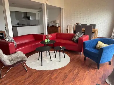 a living room with a red couch and two chairs at Seljesanden Apartment in Selje