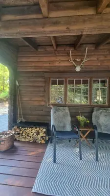 a wooden cabin with two chairs and a fireplace at Skogshytte in Holmøyane